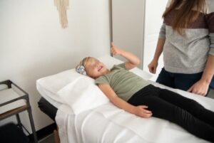 A Child on an acupuncture bed giving thumb up, practitioner standing next to her